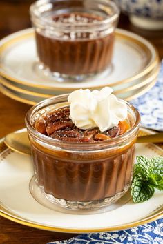 two desserts with whipped cream and fruit in them sitting on gold rimmed plates