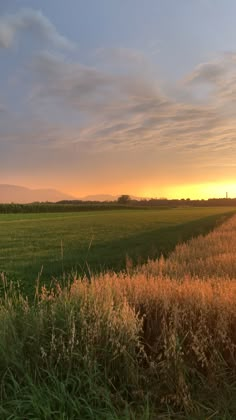 the sun is setting over an open field