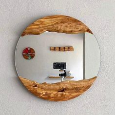 a round mirror mounted to the side of a wall next to a wooden shelf with two corks on it