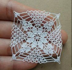 a hand holding a piece of white crochet