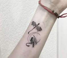 a woman's arm with a black and white tattoo design on the left wrist