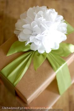 a large white flower sitting on top of a brown present box with green ribbon around it