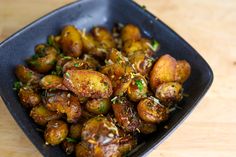 a black bowl filled with fried potatoes on top of a wooden table