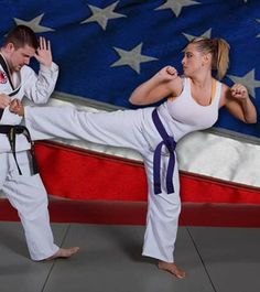 two people in front of an american flag, one kicking the other with his leg