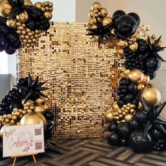 some black and gold balloons are in front of a large wall with an image on it