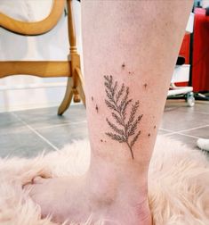 a woman's foot with a small plant tattoo on the left side of her leg