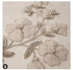 some white flowers and leaves are on a table cloth with silver chains attached to them