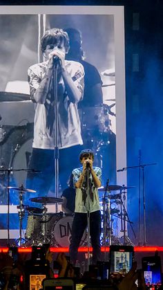 a man standing on top of a stage next to a microphone in front of a large screen