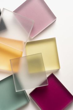 several different colored glass squares on a white surface