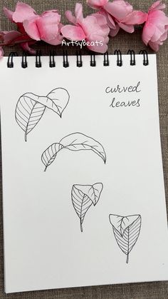 a notepad with drawings of leaves and flowers on it next to a spiral notebook