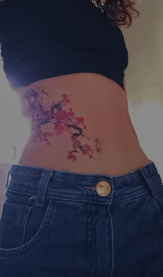 a woman's stomach with a tattoo on the side and flowers growing out of it