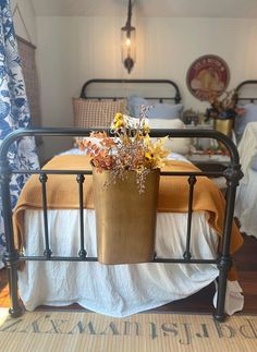 a bed with a metal frame and flower pot on the headboard in front of it