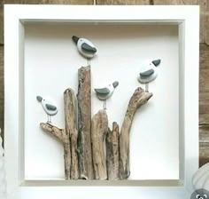 three birds perched on driftwood in a white frame