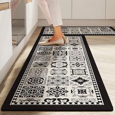 a woman standing on top of a black and white rug next to a kitchen counter