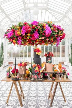 a table topped with lots of cakes covered in pink and orange flowers on top of it