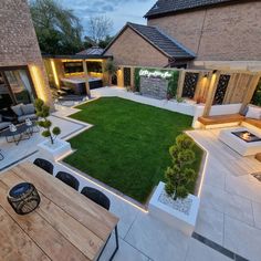 an outdoor area with wooden tables and chairs, lights on the walls and grass in the middle