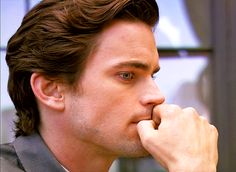 a close up of a person wearing a suit and tie with his hand on his chin