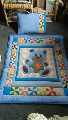 a blue teddy bear quilted on top of a bed next to two pillow cases