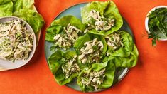 lettuce wraps with chicken and herbs on a plate next to small bowls of salad