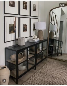 a living room with pictures on the wall and a table in front of a mirror