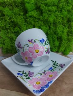 a tea cup and saucer sitting on top of a white plate with pink flowers