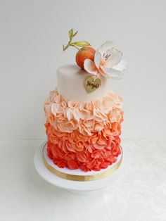 a white and orange cake with an apple on top, decorated with ruffles