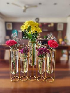 four vases with flowers in them sitting on a wooden table next to a couch