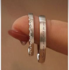 two silver rings with words on them are held in someone's hand and the other is