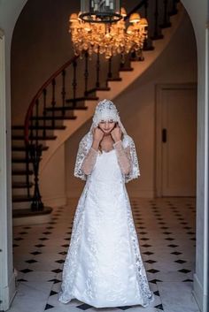 a woman in a white wedding dress is standing by the stairs with her hands on her face