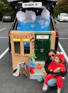 a woman holding a child in her arms next to a car trunk with decorations on it