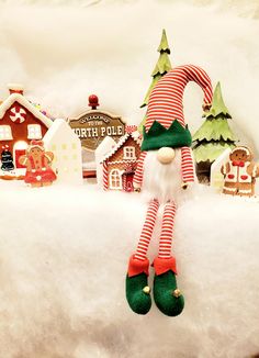 an elf doll sitting on top of a pile of snow next to other christmas decorations