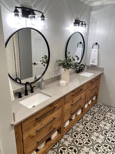 a bathroom with two sinks, mirrors and lights on the wall next to each other