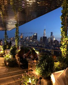 people sitting at tables on top of a roof with the city skyline in the background