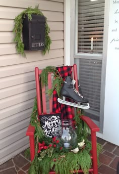 a red rocking chair sitting in front of a house with christmas decorations on the porch