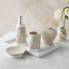 a bathroom set with soap dispenser, toothbrush holder and seashells