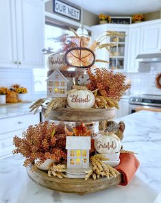 a three tiered tray with pumpkins and gourds on it in a kitchen