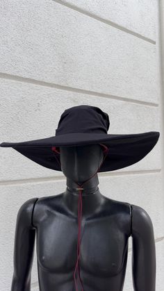 a mannequin wearing a black hat with red string attached to the brim