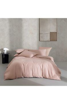 a bed with pink sheets and pillows in a room