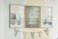 three framed pictures hang on the wall above a crib with bunting and flags