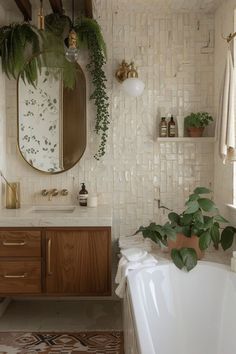 a bath room with a tub a mirror and some plants on the wall next to it