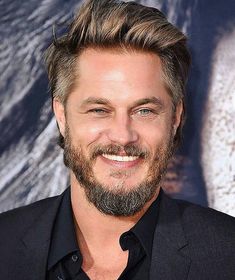 a close up of a person wearing a suit and smiling at the camera with a beard