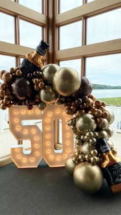 A chrome gold, brown and copper balloon garland with whiskey bottle mylar balloon accents drape over a lit up number 50 marquee for a milestone birthday celebration. 50th Birthday Restaurant Decor, 60th Birthday Balloon Marquee, 60 Birthday Balloon Ideas, Whiskey Balloon Decor, 50th Birthday Set Up, Aged To Perfection Balloons, Birthday Marquee Ideas, Birthday Decorations 50th Man, Aged To Perfection Balloon Garland