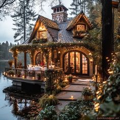 a house that has lights on the front and side of it in the middle of water