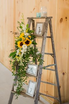 a ladder decorated with sunflowers and greenery next to a wooden paneled wall