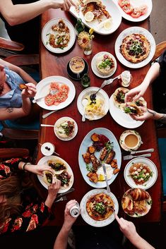 several people sitting at a table with plates of food on it and eating from bowls