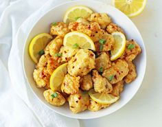 a white bowl filled with chicken and lemons