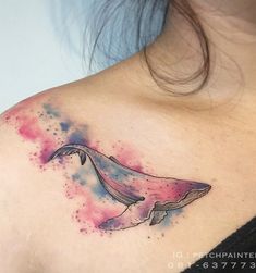 a watercolor whale tattoo on the back of a woman's shoulder