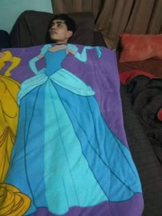 a young boy laying in bed under a blanket with princesses on it and sleeping