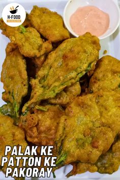 some fried food on a white plate with dipping sauce in the bowl next to it