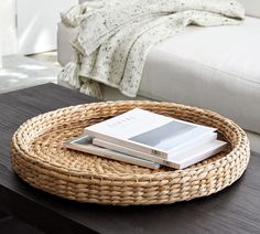 a wicker tray with two books on it and a white couch in the background